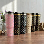 A row of six colorful stainless steel tumblers with a repeating pattern of the "V" logo, arranged on a wooden surface.